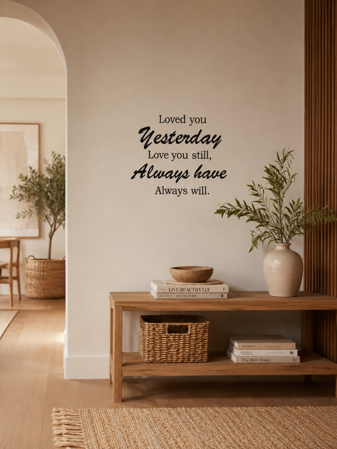 Black “Loved you Yesterday, Love you still, Always have, Always will” removable wall decal displayed in a warm boho modern hallway with neutral decor, timber console table, woven textures and indoor greenery.
