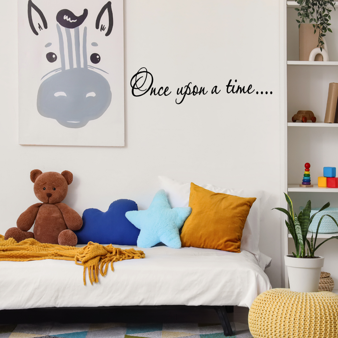 Children's bedroom with a bed, teddy bear, and decorative pillows, featuring a 'Once Upon a Time' wall decal. Two Little Giggles Wall Decal fairy princess dreams