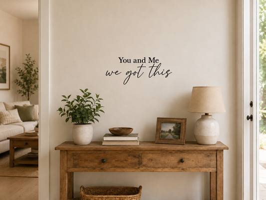 Black “You and Me we got this” removable vinyl wall decal displayed above a sofa in a warm modern living room with neutral décor and soft coloured cushions.