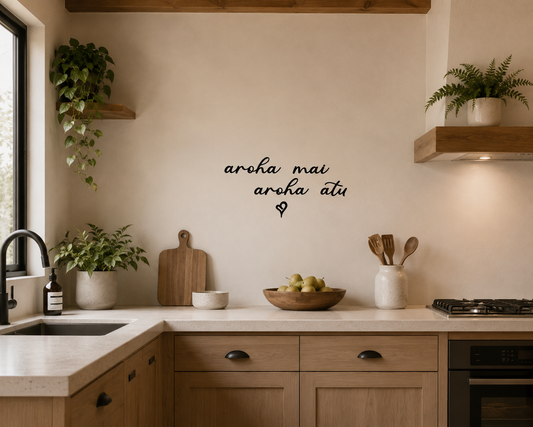 Aroha Mai Aroha Atu removable vinyl wall decal displayed above wooden drawers in a warm modern New Zealand home interior.