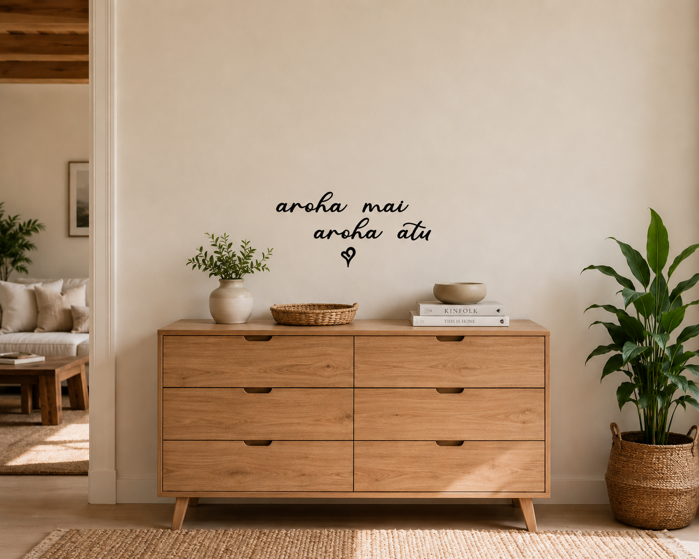 Aroha Mai Aroha Atu removable vinyl wall decal displayed above wooden drawers in a warm modern New Zealand home interior.