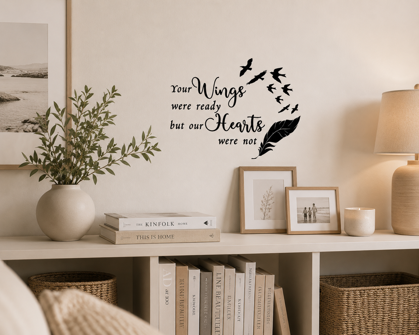 Memorial wall decal reading “Your Wings Were Ready But Our Hearts Were Not” displayed above a wooden shelf in a warm lived-in neutral home with books, plants and family decor.