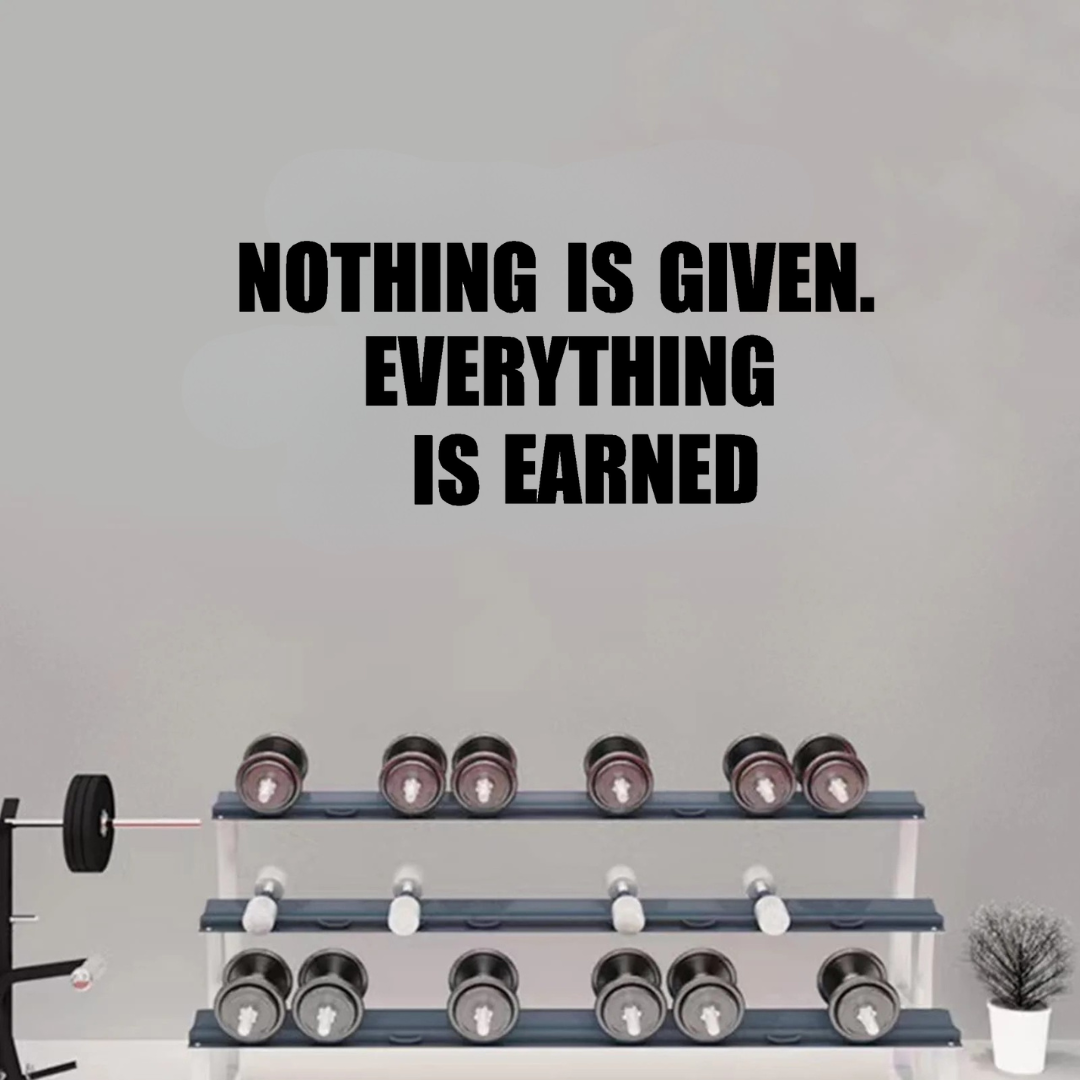 Motivational quote 'Nothing is given. Everything is earned' on a gray wall with dumbbells below.