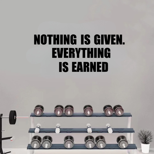 Motivational quote 'Nothing is given. Everything is earned' on a gray wall with dumbbells below.