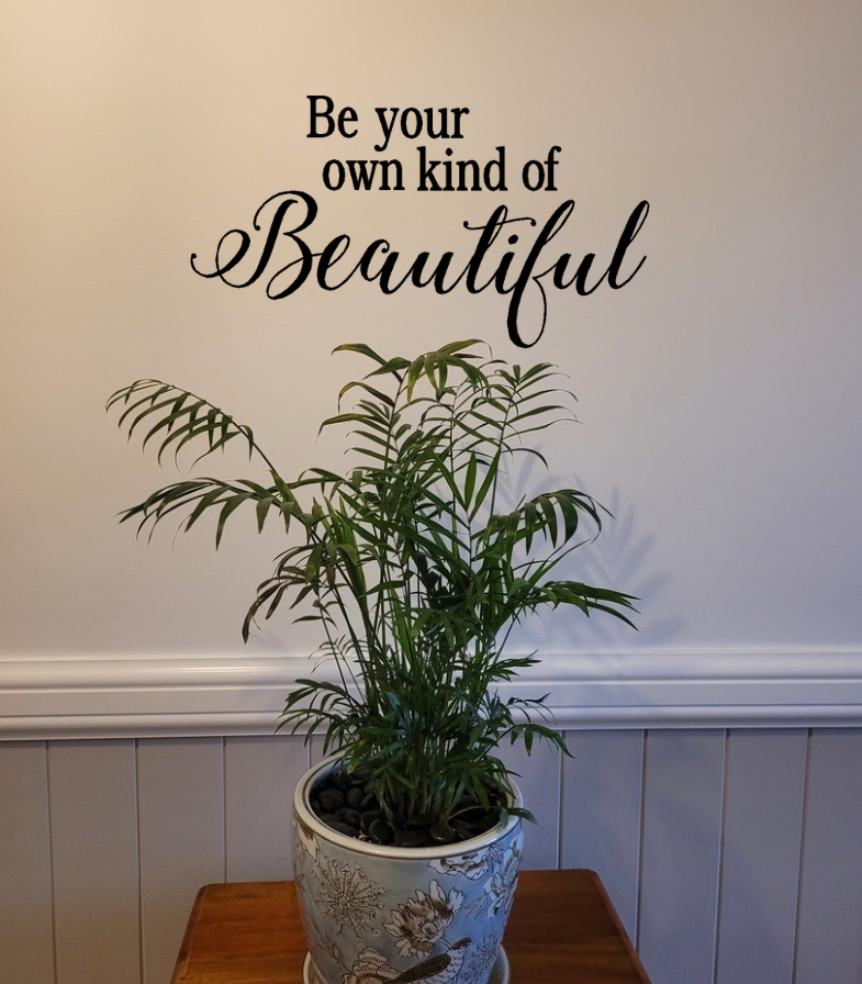 Potted plant on a wooden surface with a motivational quote on the wall behind. Two LIttle Giggles Wall Decal Sticker Quote  it.