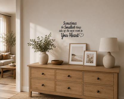Black nursery quote wall decal reading “Sometimes the smallest things take up the most room in your heart” displayed above timber drawers in a warm neutral family home.