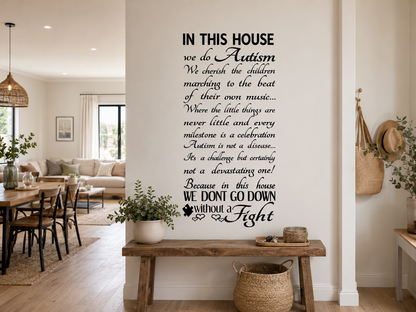 Black “In This House We Do Autism” wall decal displayed in a warm neutral open-plan hallway with timber bench seating and casual Scandinavian style décor.
