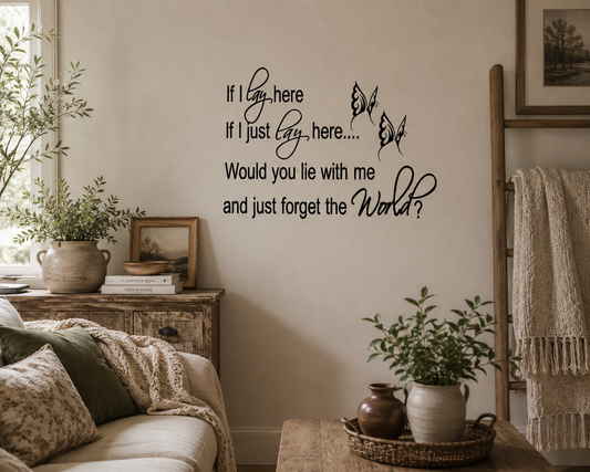 Living room with a wall decal, plants, and a couch. Black romantic quote wall decal with butterfly details displayed in a cosy neutral-toned living room with rustic décor and soft natural lighting.