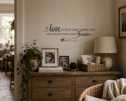 Black memorial quote wall decal reading “If Love Could Have Saved You You Would Have Lived Forever” displayed above rustic timber drawers in a warm neutral styled home interior.