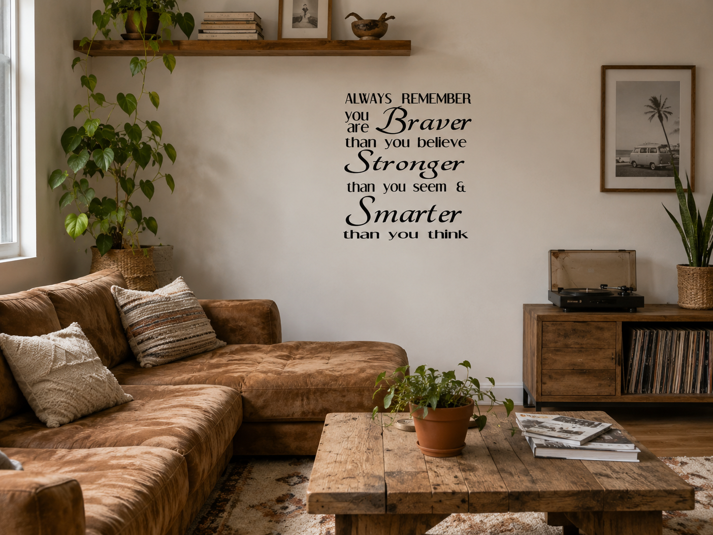 A beautiful modern living room featuring a motivational wall decal reading “Always Remember You Are Braver Than You Believe, Stronger Than You Seem & Smarter Than You Think” displayed above a fireplace with neutral décor and indoor plants.