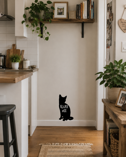 Black “Fluff Off” cat wall decal placed low on a hallway wall in a cosy lived-in home with timber furniture and indoor plants.