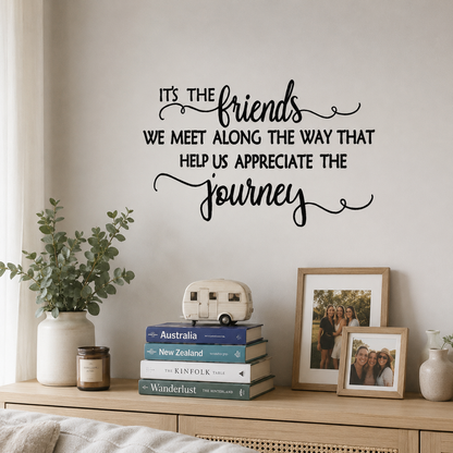 Black friendship quote wall decal above a wooden shelf with books, framed photos, and home decor in a Scandinavian-style living room.