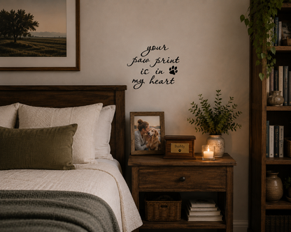 Paw Prints removable vinyl wall decal displayed above a bedside table with framed pet photos in a warm modern bedroom.